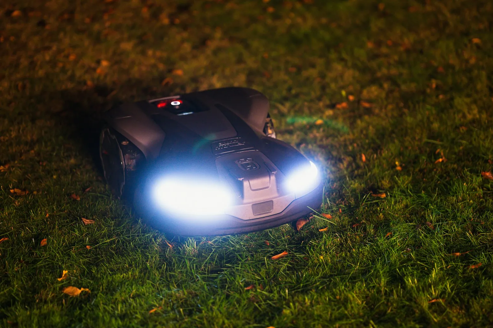Autonomiczna kosiarka z reflektorami LED na gęstym trawniku