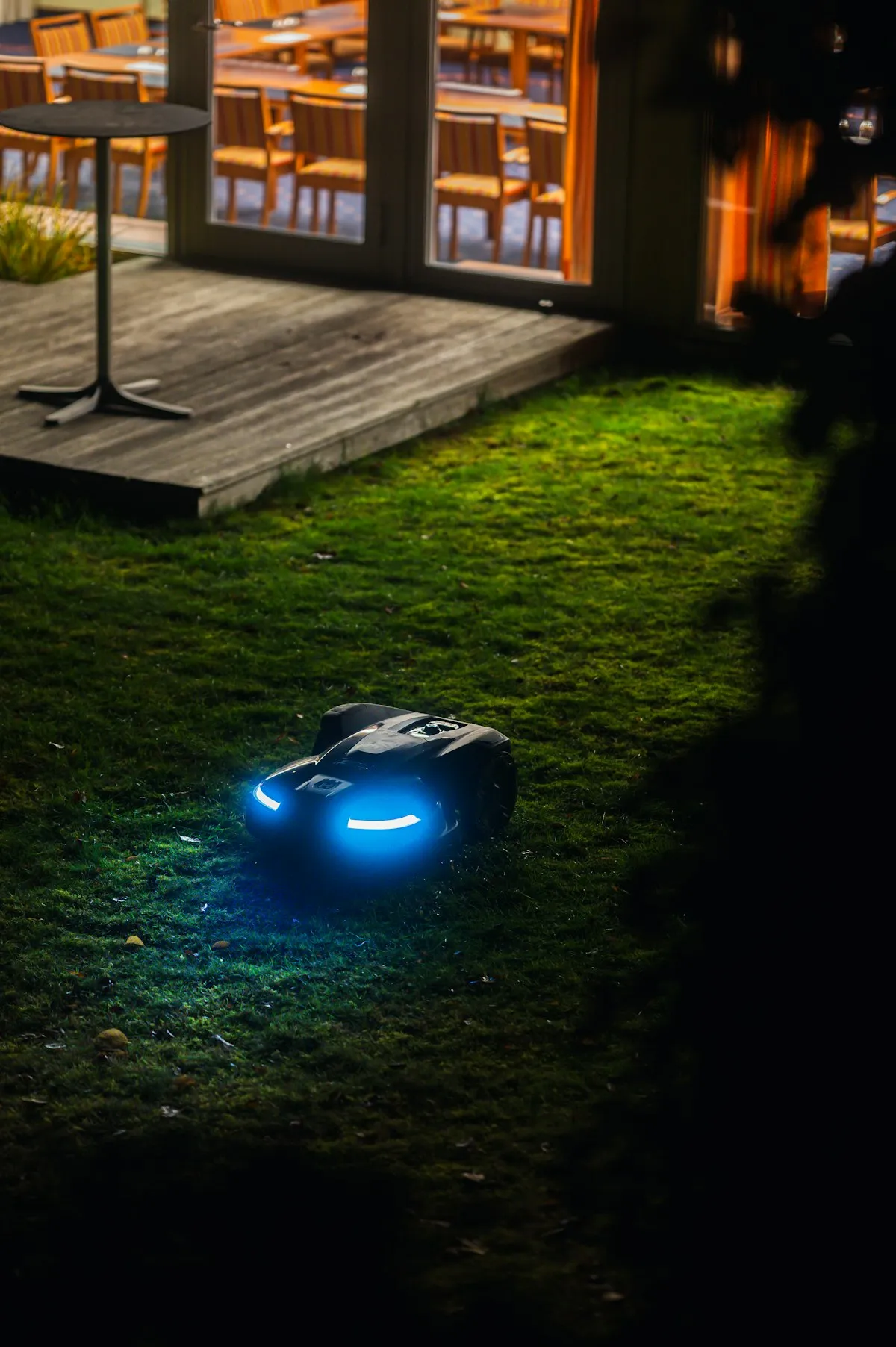 Robot koszący przy drewnianym tarasie po zmroku